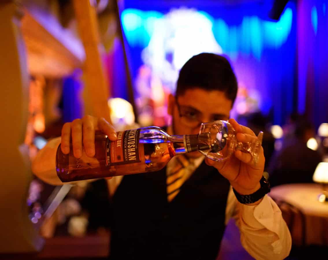 A bartender carefully pours whiskey in to a glass
