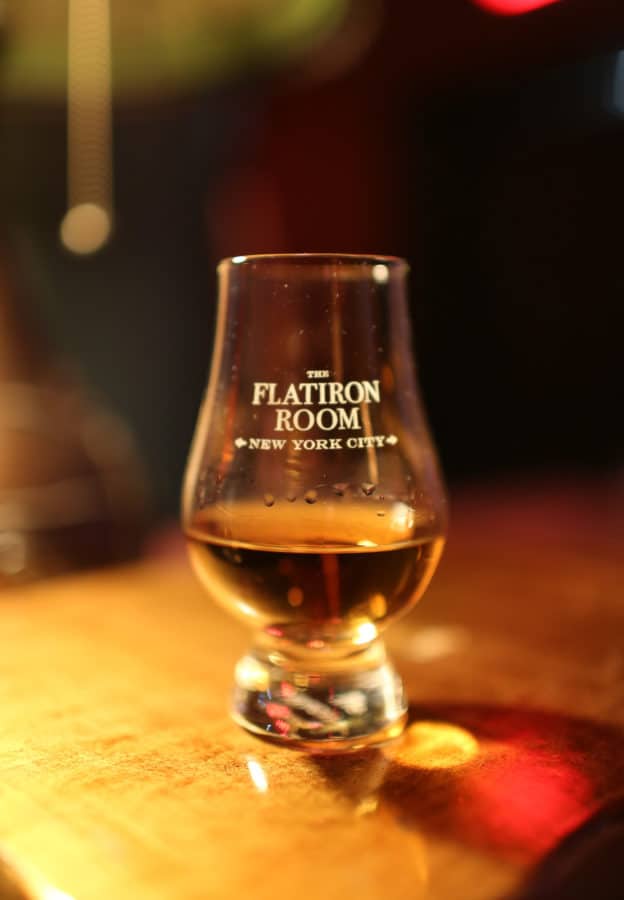 A Flatiron Room glass with whiskey in it